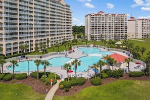 A hotel complex with multiple buildings, a central swimming pool, and surrounding greenery. - Golf-range View- Slps 11-Beach Shuttle-Grill- Pool (North Myrtle Beach)