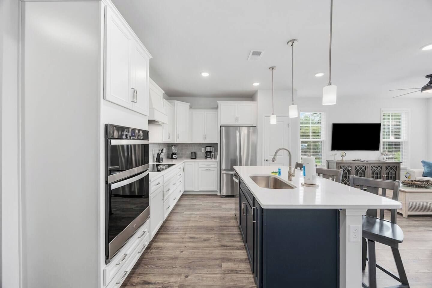 Una cocina moderna con armarios blancos, electrodomésticos de acero inoxidable y una isla grande con pileta.