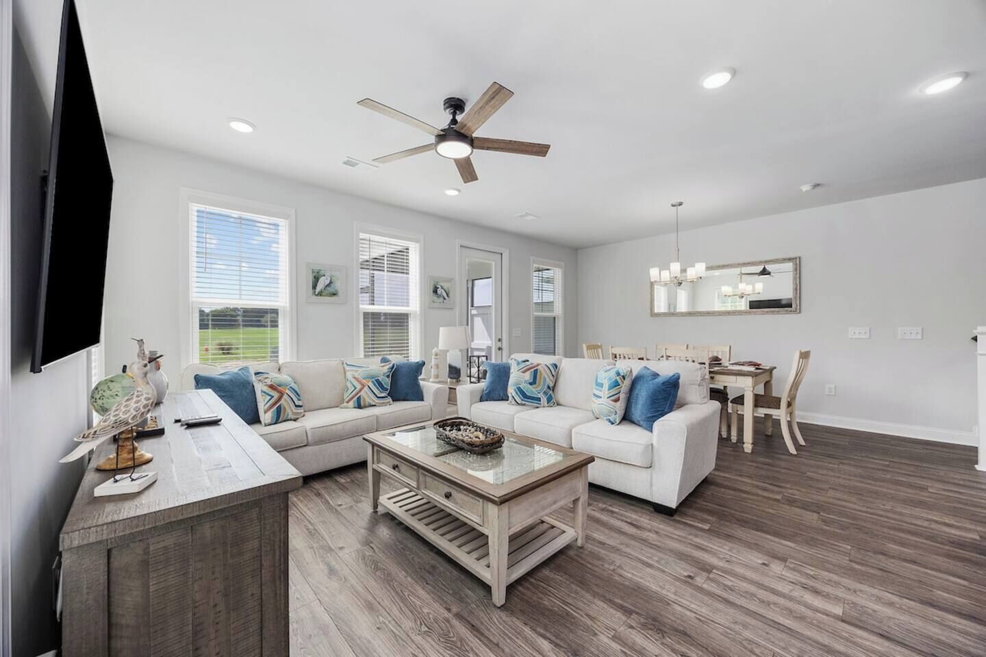 A modern living room with a sectional sofa, a coffee table, and a dining area with a wooden table and chairs.