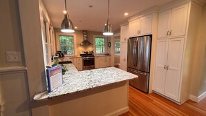 Una cocina moderna con encimeras de granito, electrodomésticos de acero inoxidable y armarios blancos.
