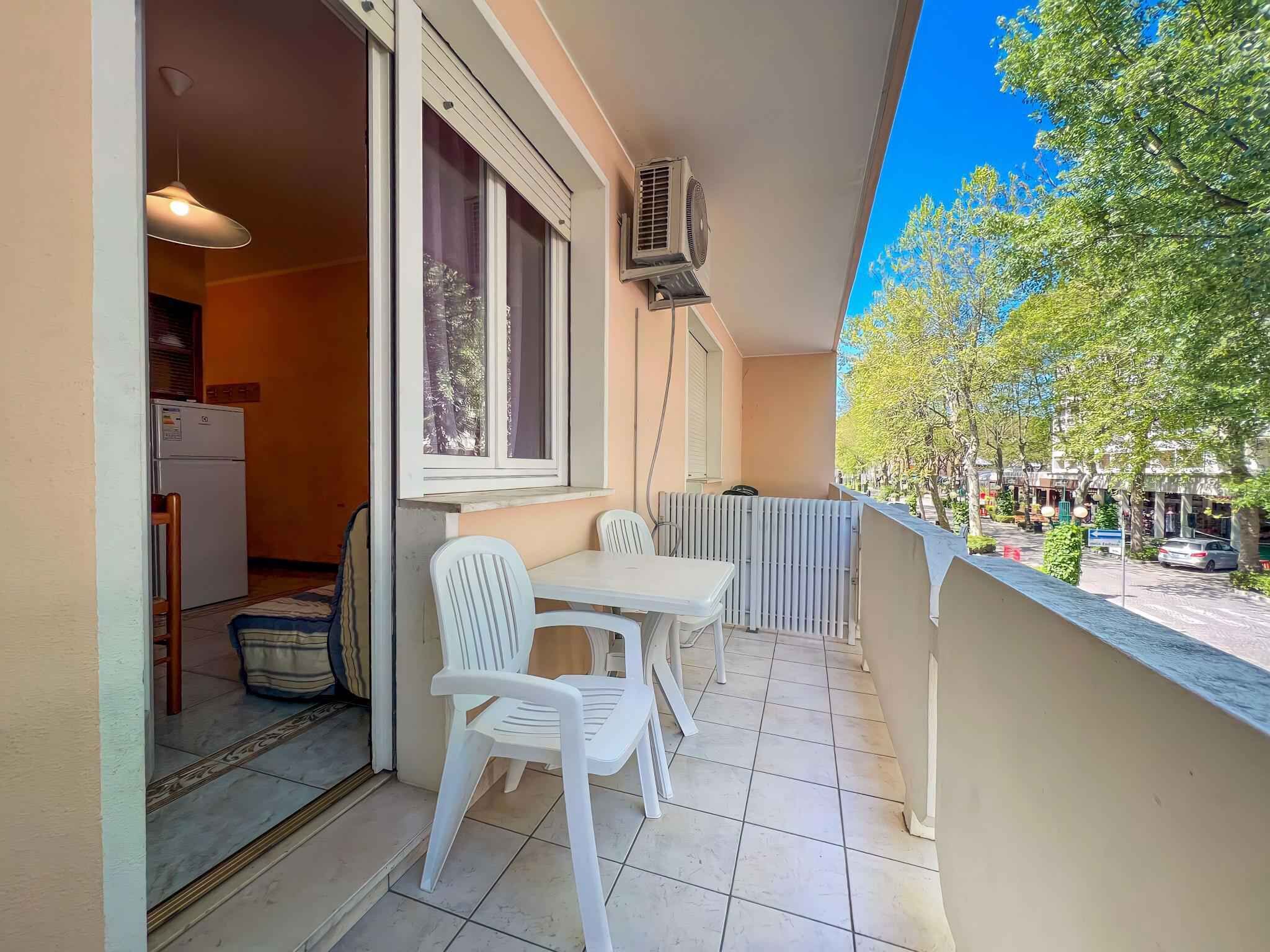 Een balkon met een tafel en stoelen, een radiator en een raam met airconditioning.