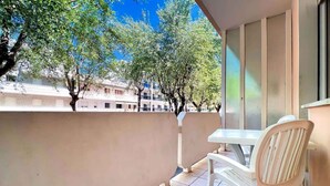 Un balcón con una mesa y sillas, con vista a una zona residencial con árboles y edificios.
