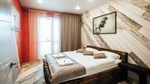 Ein Schlafzimmer mit einem hölzernen Bett, einem Fenster mit Vorhängen und einem gerahmten Bild an der Wand.