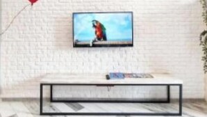 Ein modernes Wohnzimmer mit einer weißen Ziegelwand, einem Wand-Fernseher, einem TV-Schrank mit schwarzem Rahmen und einem roten, herzförmigen Luftballon.