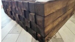 Ein Bett mit einem Holz-Kopfteil und einem weißen Bettlaken.