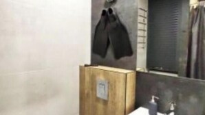 Un bagno moderno con box doccia in legno, un lavandino bianco con specchio e un porta asciugamani.