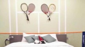 Una camera d'albergo con un letto, cuscini e due racchette da tennis appese al muro.