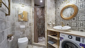 A bathroom with a toilet, sink, shower, and washing machine.