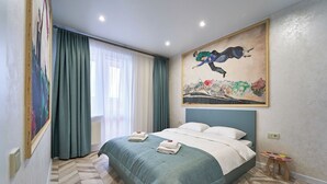 A hotel room with a bed, a painting, and a small table.
