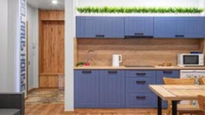 Een moderne keuken met blauwe kastjes, een houten aanrecht en een magnetron.