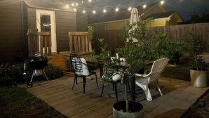 Eine Terrassengruppe mit Tisch, Stühlen, Lichterkette und Topfpflanzen.