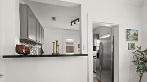 Eine moderne Küche mit Edelstahlgeräten, einer schwarzen Arbeitsfläche und einem Essbereich mit Tisch und Stühlen.