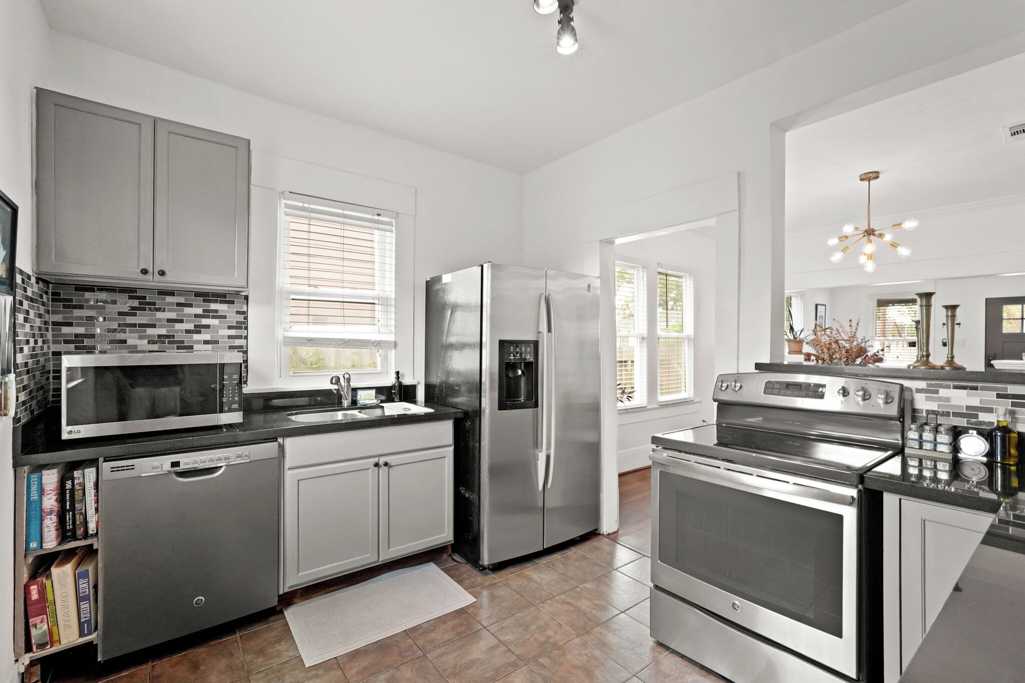A modern kitchen with stainless steel appliances, white cabinetry, and a tiled backsplash.