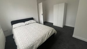 Een slaapkamer met een bed, een kast en een deur.