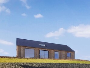 A modern wooden building with large windows and a sloped roof. - 3 bedroom accommodation in Portree, Isle of Skye (Portree, Isle of Skye)