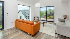 Una sala de estar moderna con un ventanal grande, un sofá, una silla y una mesa.