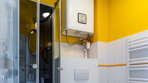 Un baño moderno con ducha de vidrio, inodoro y calentador de agua blanco.