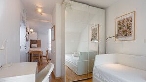 Una habitación de hotel moderna con un armario espejo, una cama, un escritorio y una silla.