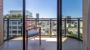 A balcony with a chair, a view of a cityscape, and a tiled floor. - (1402) 2 Suítes, Vista para o Mar e Cristo (Rio de Janeiro)