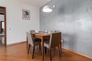 A dining area with a wooden table, four chairs, and a pendant light. - (1402) 2 Suítes, Vista para o Mar e Cristo (Rio de Janeiro)