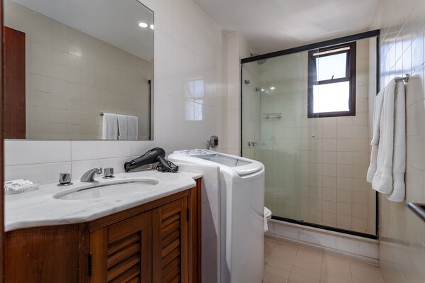 A modern bathroom with a double sink, a hairdryer, and a glass-enclosed shower. - (1402) 2 Suítes, Vista para o Mar e Cristo (Rio de Janeiro)