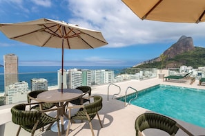 A rooftop pool area with a view of the ocean and a mountain. - (1402) 2 Suítes, Vista para o Mar e Cristo (Rio de Janeiro)