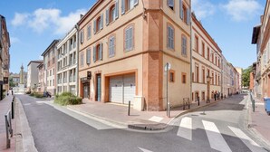 A street with buildings on both sides, a clear sky, and a pedestrian crossing.