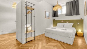 A bedroom with a bed, a wardrobe, a hanging light fixture, and a window with curtains.