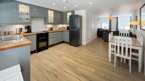 A modern kitchen with grey cabinets, a black refrigerator, and a wooden dining table with white chairs. - 3 bedroom accommodation in Coldstream, near Kelso (Coldstream, near Kelso)