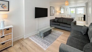 A modern living room with a grey sofa, a flat-screen TV, wicker baskets, and a patterned rug. - 3 bedroom accommodation in Coldstream, near Kelso (Coldstream, near Kelso)
