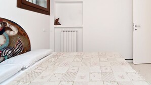 A bedroom with a bed, a radiator, a door, and a window with a wooden frame. - San Polo Apartment by Ca-sa Check (Venice)