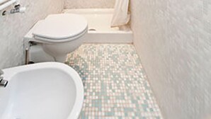 A small, narrow bathroom with a toilet, a sink, and a shower stall. - San Polo Apartment by Ca-sa Check (Venice)