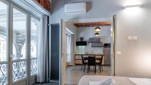 A modern hotel room with a large bed, a dining area, and a kitchen. - Suite Queen Apartments (Turin)