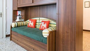 Un letto in legno con una coperta verde e cuscini a righe.