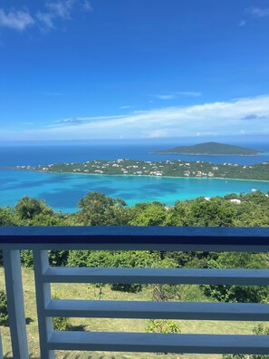 A coastal view with a clear sky, turquoise waters, and a distant island.