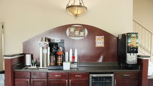 A kitchen with a coffee machine, a refrigerator, and a juice dispenser. - Boarders Inn & Suites (Lamar)