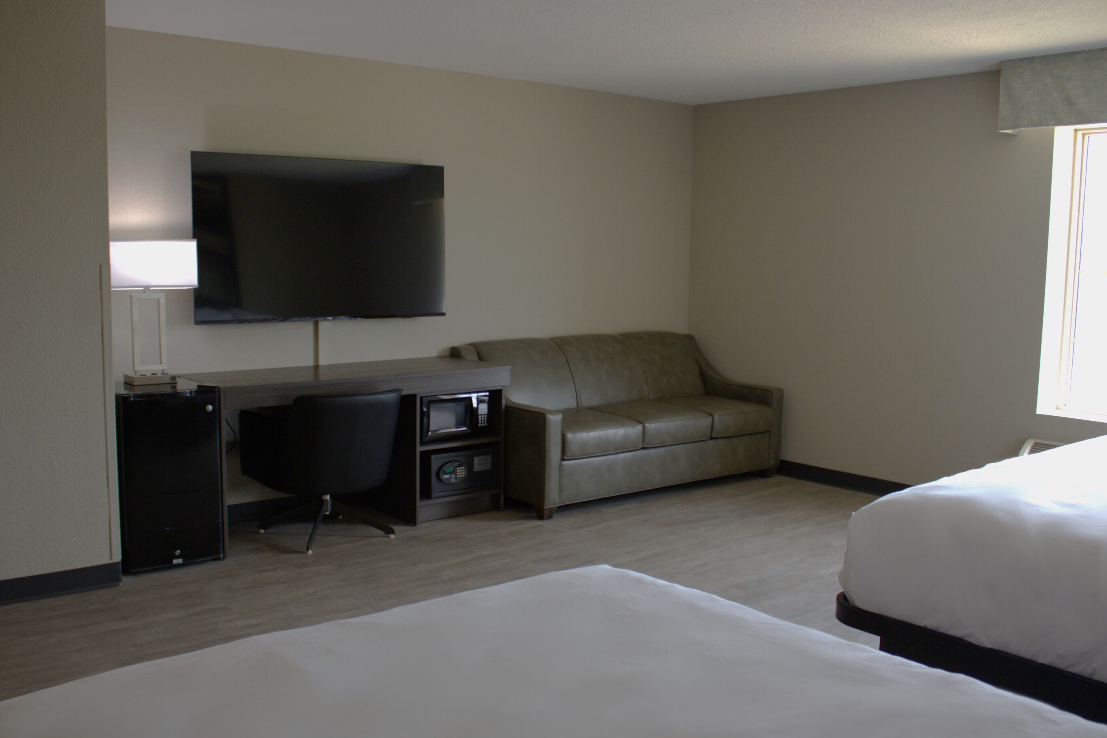 A hotel room with a bed, a desk with a computer, a television, and a sofa.