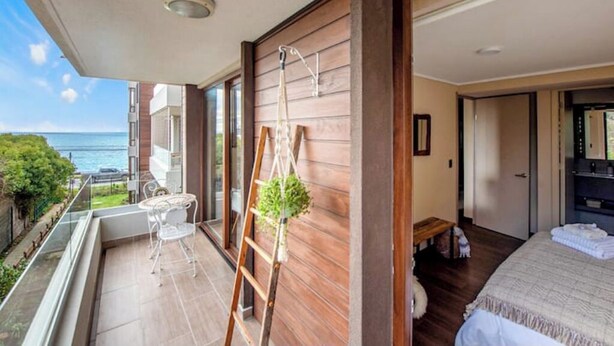 A balcony with a view of the sea, a wooden wall, a ladder, and a small table with chairs. - 5 star apartment in the Costanera del Lago (Puerto Varas)