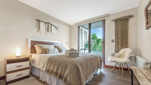 A bedroom with a bed, bedside table, chair, and a window with curtains. - 5 star apartment in the Costanera del Lago (Puerto Varas)