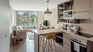 A modern kitchen with a central island, built-in appliances, and a dining area with a sofa and chairs. - 5 star apartment in the Costanera del Lago (Puerto Varas)