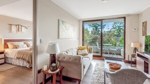 A modern bedroom with a bed, bedside table, lamp, and a view of the outdoors through a sliding glass door. - 5 star apartment in the Costanera del Lago (Puerto Varas)