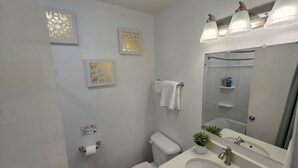 A bathroom with a toilet, sink, mirror, and wall-mounted towel rack.