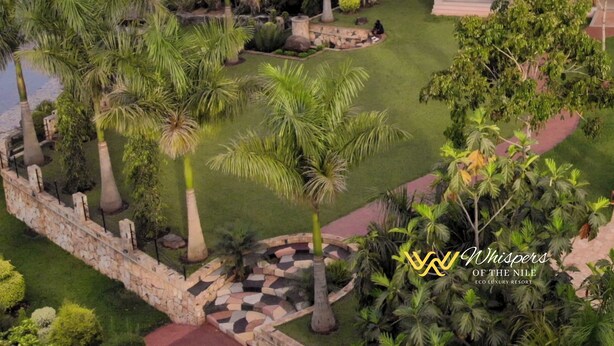 An eco luxury resort with a thatched-roof pavilion, lush greenery, and a river view.