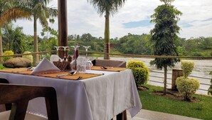 A table set for dining with a view of a river and greenery.