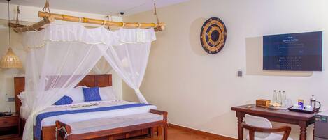 A room with a bed, a desk, a chair, a television, and a wall-mounted screen.