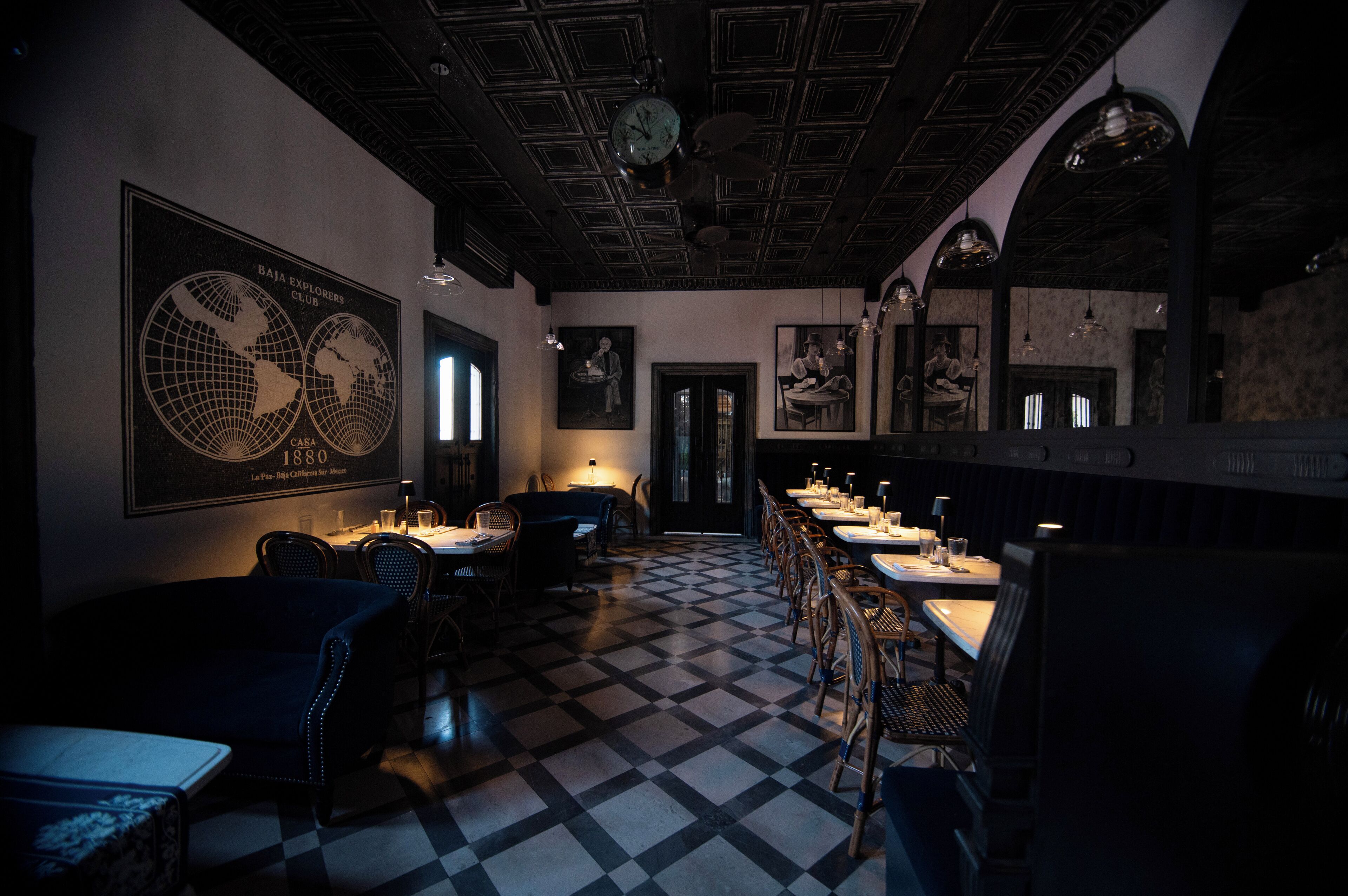Un restaurant amb un terra de pissos quadriculats, un sostre de fusta fosca i taules amb caires.