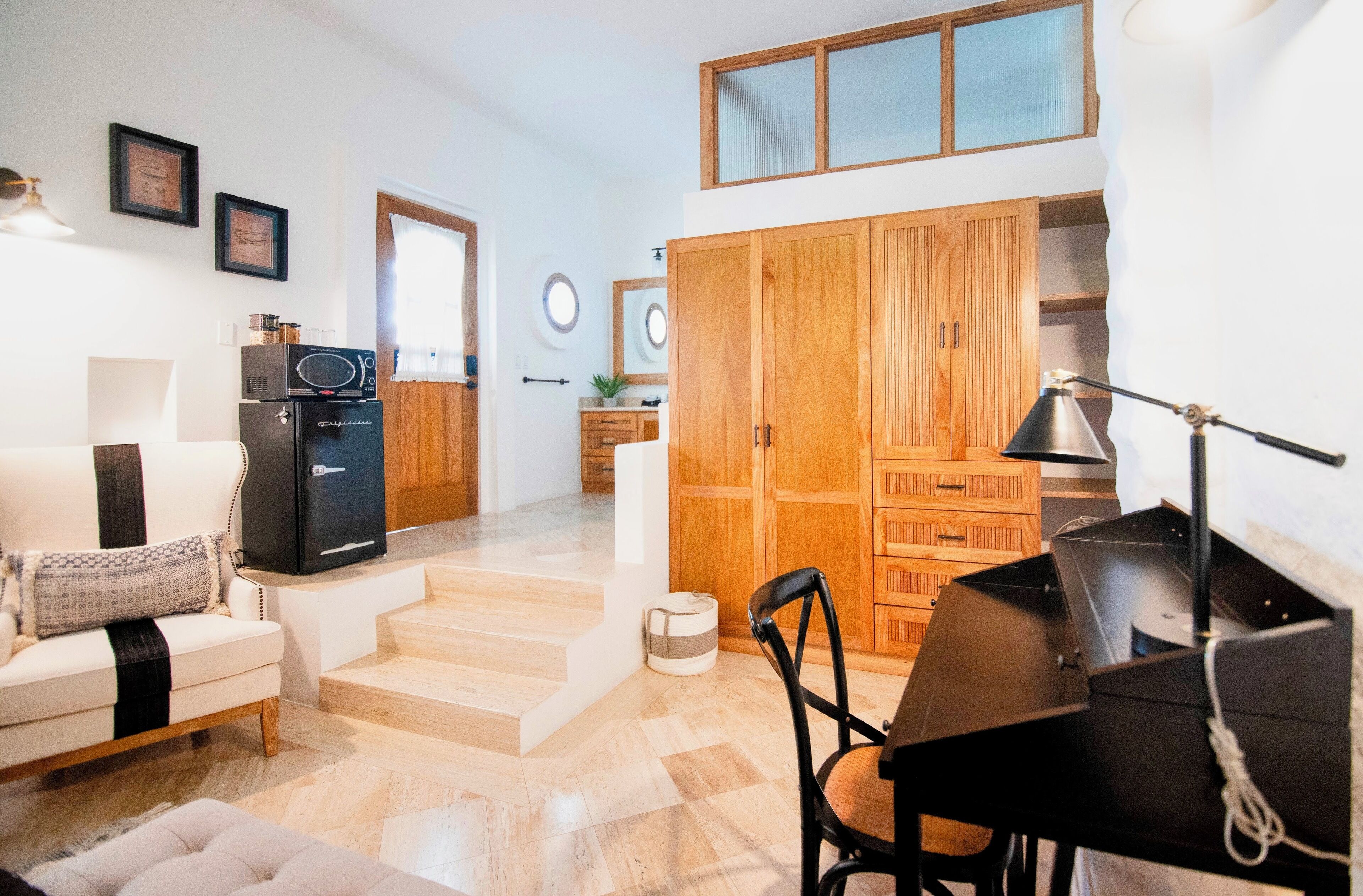 A compact living space with a sofa, a dining table, a kitchenette, and a wooden wardrobe.