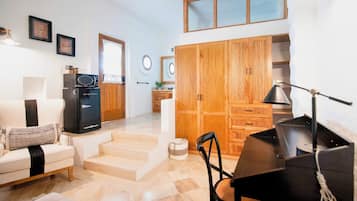 A compact living space with a sofa, a dining table, a kitchenette, and a wooden wardrobe.