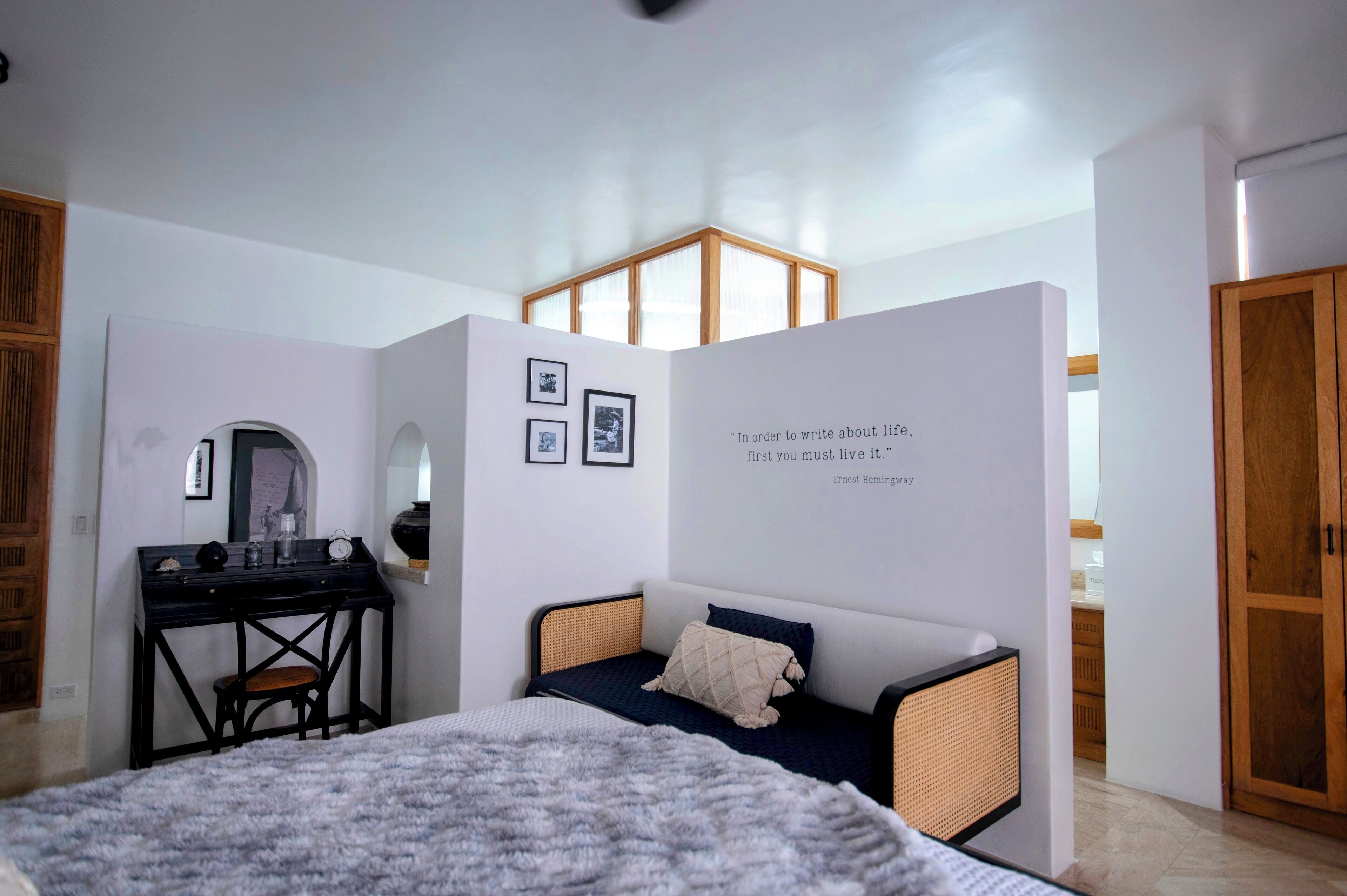 A bedroom with a bed, a desk, and a wardrobe.