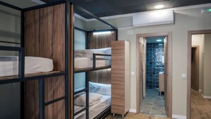 A bunk bed room with a wooden wardrobe and a bathroom visible through a glass door. - SOM HOSTEL BOUTIQUE  (Valencia)